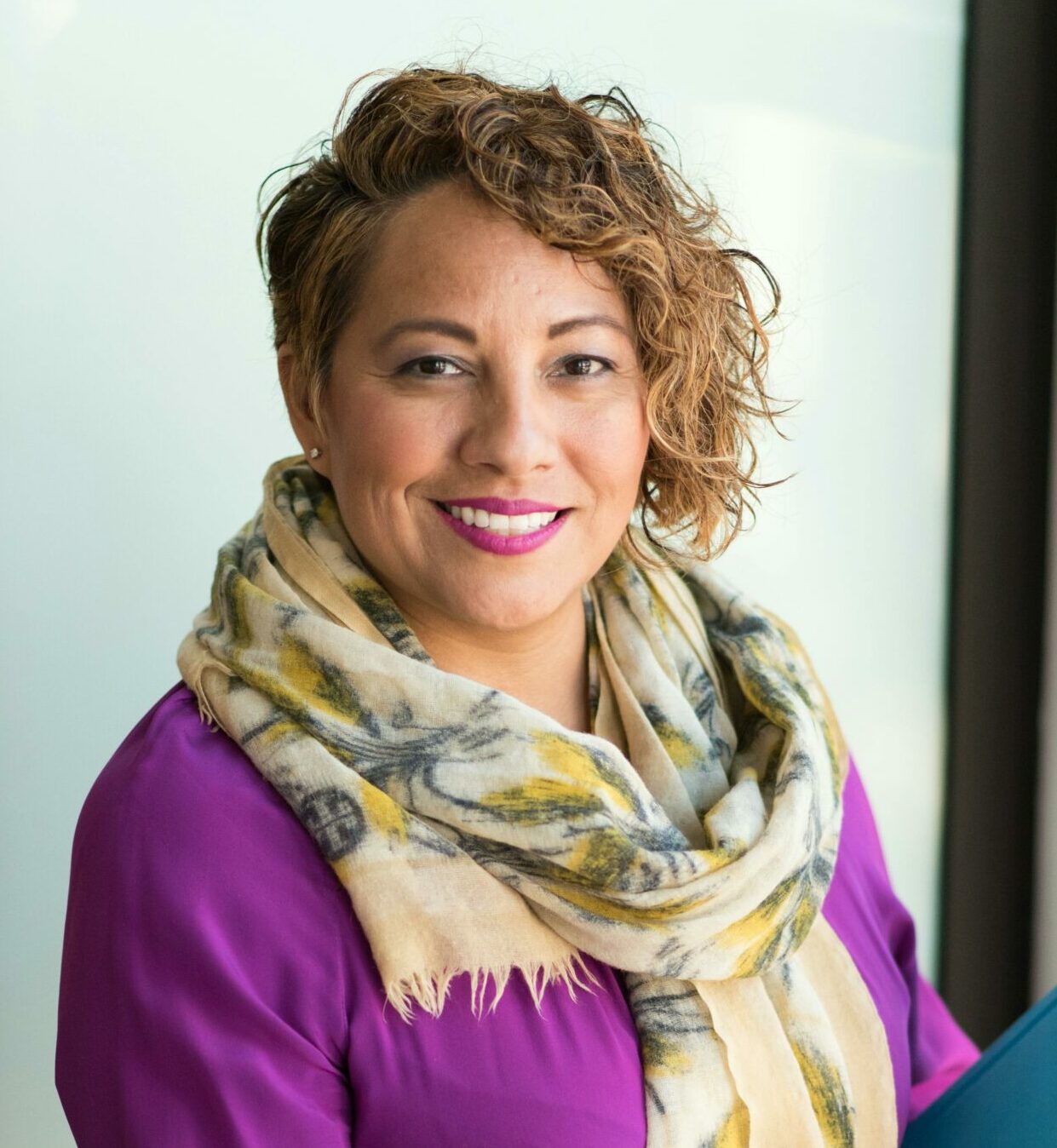 Woman Smiling and Holding Teal Book